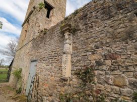 An outdoor stone wall with a carved stone figure mounted on it and a wooden door nearby at Snape Castle Garden Lodge in Snape near Bedale