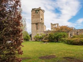 A stone tower ruin with surrounding greenery and a lawn at Snape Castle Garden Lodge in Snape near Bedale