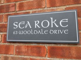 A house sign for Sea Roke on a brick wall at 63 Wooldale Drive