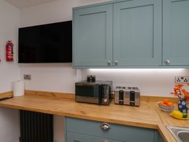 A kitchen with a microwave, toaster, and TV at Sea Roke in Filey