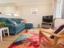 A living room with a sofa, armchair, and television at Jaspers Retreat, formerly known as Starfish Cottage, Falmouth