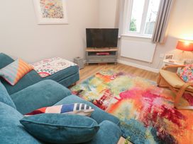 A living room with a television and colorful rug at Jaspers Retreat, formerly known as Starfish Cottage, Falmouth