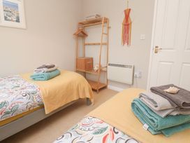 A bedroom with two beds and a shelf at Jaspers Retreat, formerly known as Starfish Cottage, Falmouth