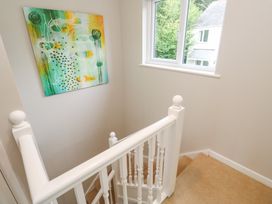 A staircase with a railing and artwork on the wall at Jaspers Retreat, formerly known as Starfish Cottage, Falmouth