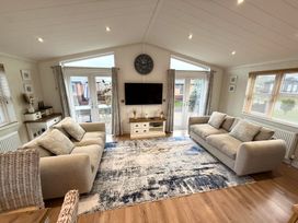 A living room with a television and large windows at Lodge 18 - The Pines Runswick Bay