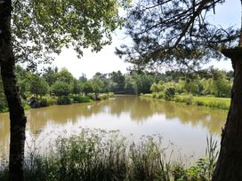 A pond surrounded by trees and grass at Maple in Dolton