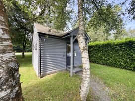 A small wooden building with a front door surrounded by trees at Maple in Dolton
