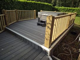 A deck with a hot tub and railing at Willow in Dolton