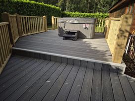 An outdoor deck with a hot tub and wooden railing at Willow in Dolton