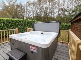 A hot tub on a deck with trees in the background at Willow in Dolton