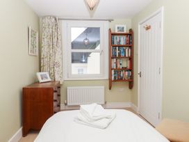 A bedroom with a bed, chest of drawers, bookshelf and window at 5 Exe Street Topsham