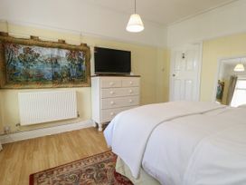 A bedroom with a bed a white dresser with a television and a wall hanging at Rhos Retreat No 7 in Rhos-On-Sea