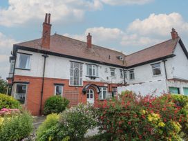 A two story brick and stucco house with chimneys and flowering bushes in front at Rhos Retreat No 7 in Rhos On Sea
