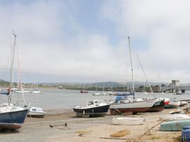 Boats on the shore near a body of water with a bridge and hills in the background at Rhos Retreat No 7 in Rhos On Sea