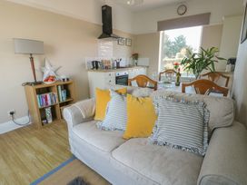 A living room with a sofa and cushions facing a dining table and kitchen at Rhos Retreat No 7 in Rhos On Sea