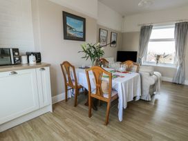 A dining table with chairs set near a window and kitchen counter in a living room at Rhos Retreat No 7 in Rhos On Sea