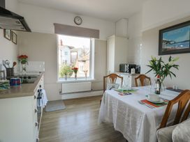 A kitchen and dining area with table and chairs next to a window with flowers in Rhos Retreat No 7 Rhos On Sea