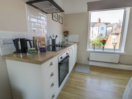 A kitchen with white cabinets wooden countertop and window showing neighboring houses at Rhos Retreat No 7 in Rhos On Sea