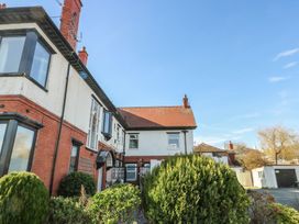 Exterior of a two story house with brick and white walls shrubs in front and blue sky at Rhos Retreat No 7 in Rhos On Sea