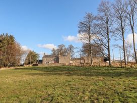 A house surrounded by trees and grass at Cragg Lodge in West Woodburn