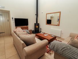 A living room with a television and wood stove at Cragg Lodge in West Woodburn