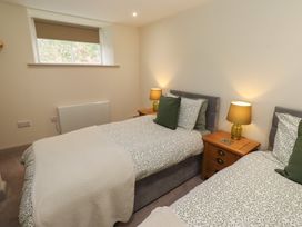 A bedroom with two beds and lamps on bedside tables at Cragg Lodge in West Woodburn