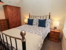 A bedroom with a bed and wooden furniture at Cragg Lodge in West Woodburn