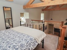 A loft bedroom with a bed and a chair at Cragg Lodge in West Woodburn