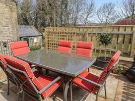 An outdoor seating area with a table and chairs at Cragg Lodge in West Woodburn