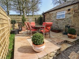 A garden with a table and chairs at Cragg Lodge in West Woodburn