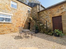 An outdoor area with a table and chairs next to a stone wall at Cragg Lodge in West Woodburn