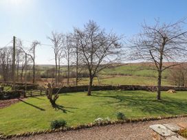 A garden with trees and a stone wall at Cragg Lodge, West Woodburn