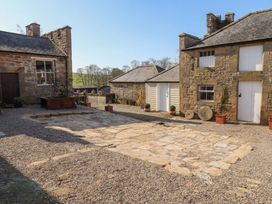 An outdoor area with stone patio and buildings at Cragg Lodge, West Woodburn