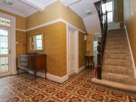 A hallway with a staircase and a chest of drawers at Southbourne Manor in Llandudno
