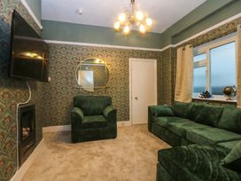 A living room with a green sofa and armchair at Southbourne Manor in Llandudno