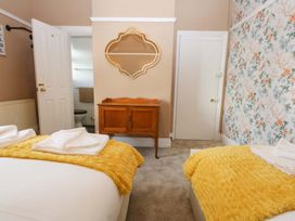 A bedroom with two beds and a wooden cabinet at Southbourne Manor in Llandudno
