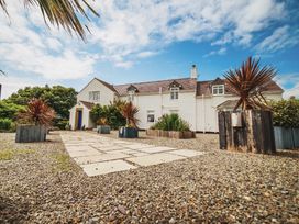 An outdoor view of a house with a gravel pathway and planters at Glanllyn Bach in Llanfaelog