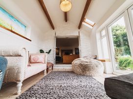 A living room with a sofa, rug, and bean bag at Glanllyn Bach in Llanfaelog