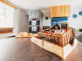 A kitchen with a basket of food and a loaf of bread at Glanllyn Bach in Llanfaelog