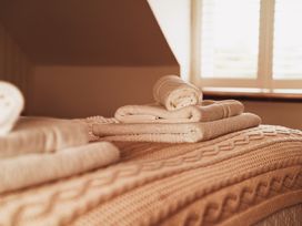 Towels and a blanket on a bed at Glanllyn Bach in Llanfaelog