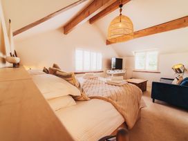 A bedroom with a bed, sofa and television at Glanllyn Bach in Llanfaelog