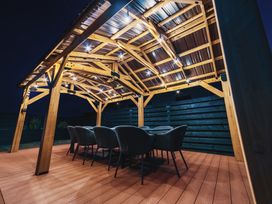 An outdoor dining area with a wooden pergola and chairs at Glanllyn Bach in Llanfaelog