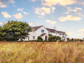 A house with trees and grass at Glanllyn Bach in Llanfaelog