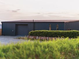 A metal building with a rolling door and windows at Glanllyn Bach in Llanfaelog