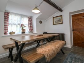 A dining room with a wooden table and benches at Tan Y Merddyn in Ceunant near Llanrug