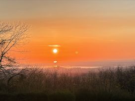 A sunset view with trees and water at Tan Y Merddyn in Ceunant near Llanrug