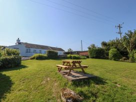 A garden with a picnic table and a house in the background at Tan Y Merddyn Ceunant near Llanrug