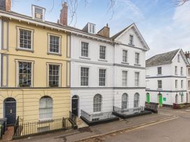 A street view of townhouses with white and yellow facades and black doors at 8 Richmond Road in Exeter
