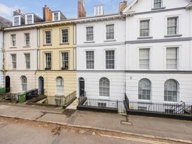 A row of terraced houses with multiple windows and black doors on a street at 8 Richmond Road in Exeter