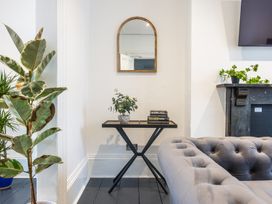 A corner with a small table holding a potted plant and books under an arched mirror next to a sofa and plants at 8 Richmond Road in Exeter